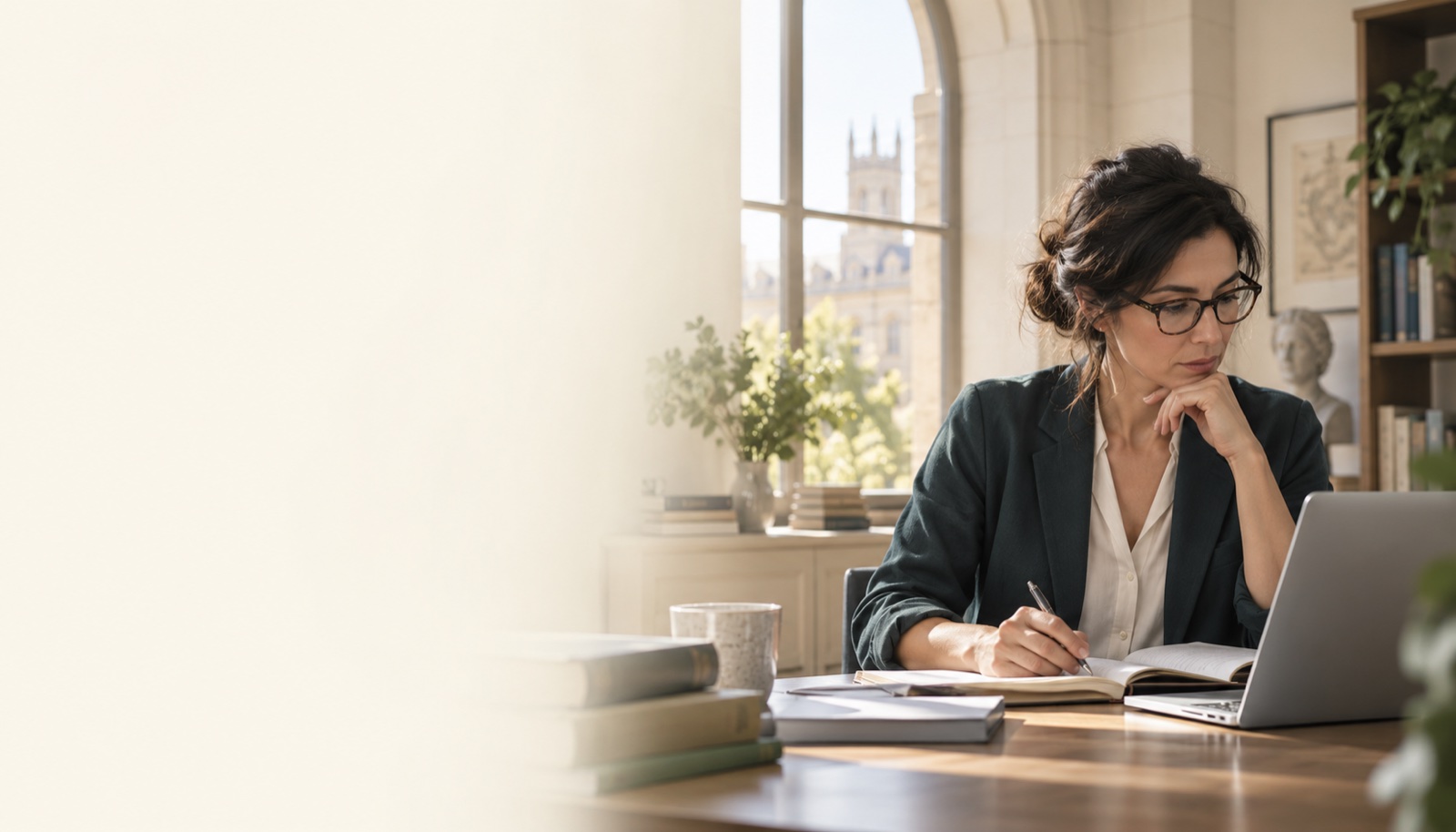 Illustrative researcher reviewing papers and making notes at a laptop
